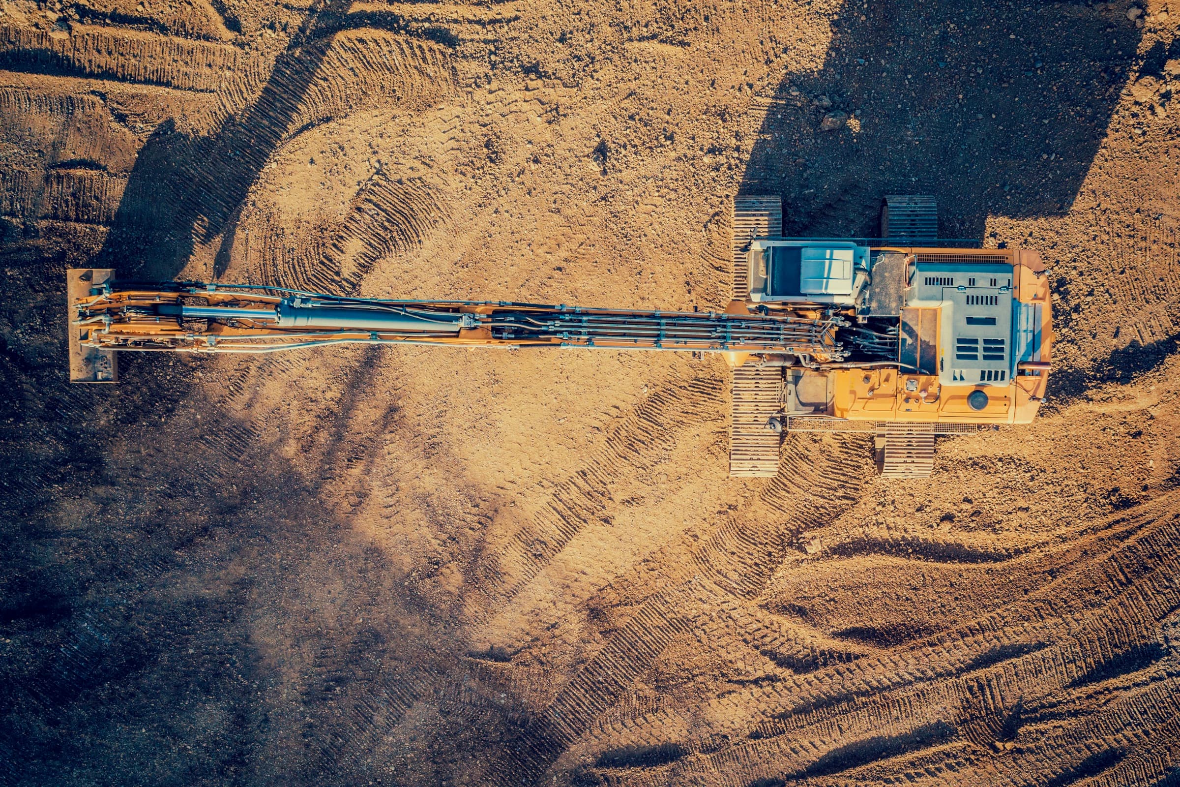 Aerial view of a tracked excavator working a graded earthworks site